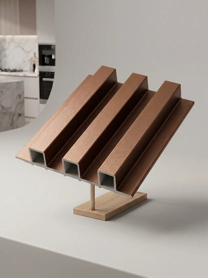A set of four copper-colored aluminum extrusion profiles with square cross-sections, mounted on a wooden display stand on a white countertop.