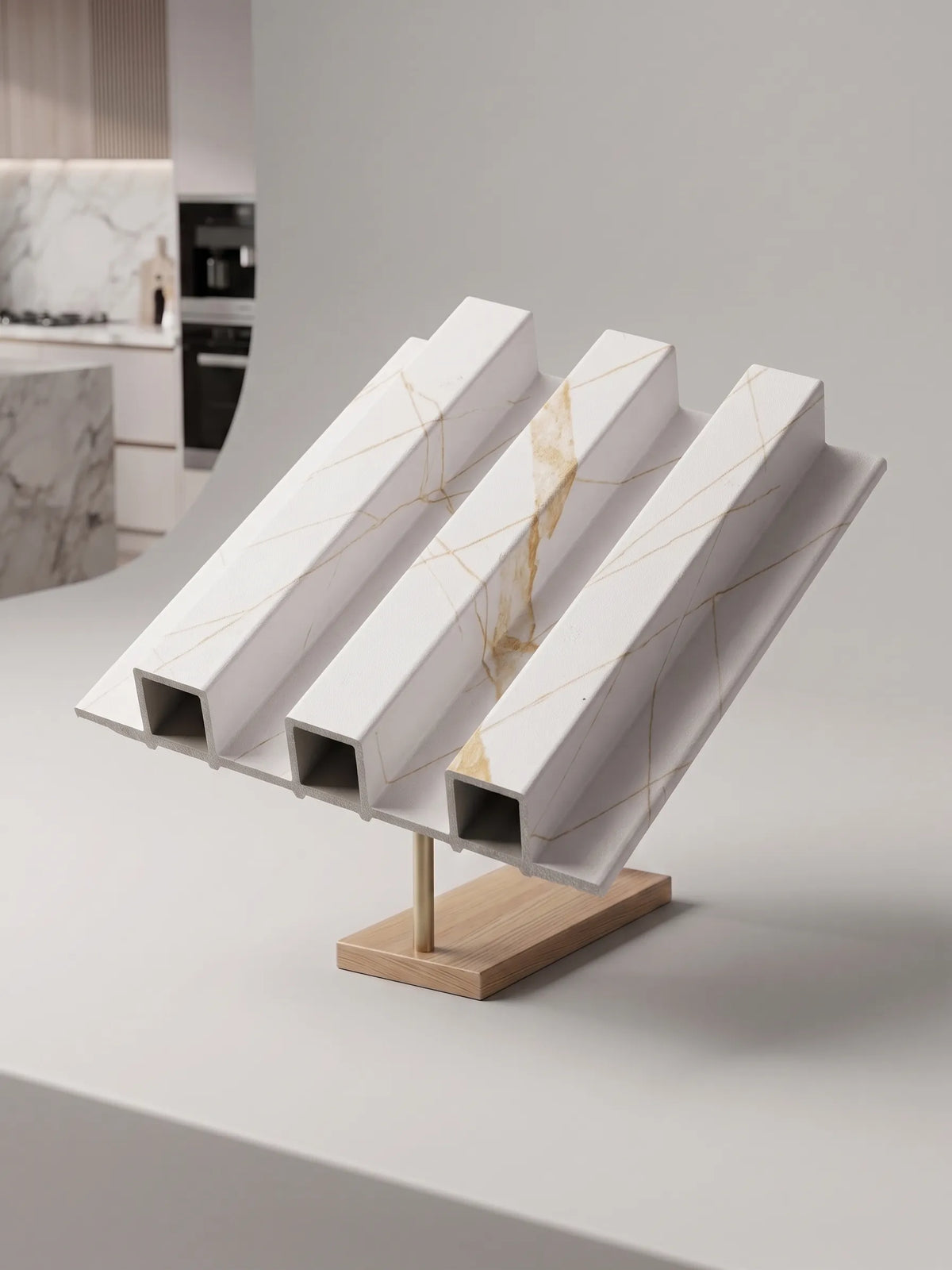 Three white marble-look square-profile metal channel beams with gold veining, displayed on a wooden stand in a modern kitchen setting.